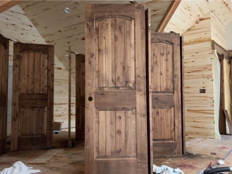 Dark-stained interior doors and wood panel walls with floors protected for spray work